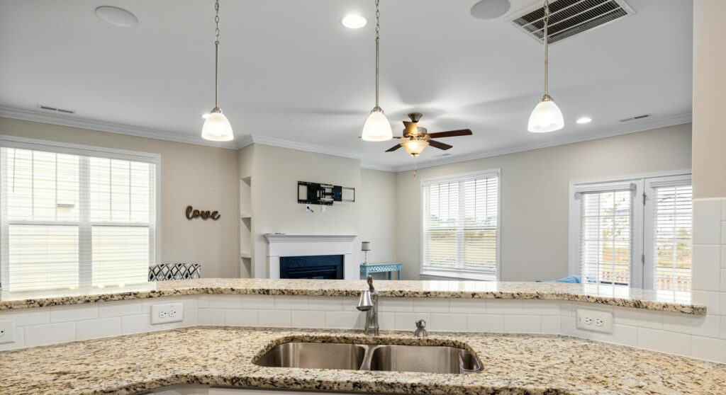Bright kitchen interior featuring granite countertops, pendant lighting, and a spacious open layout.